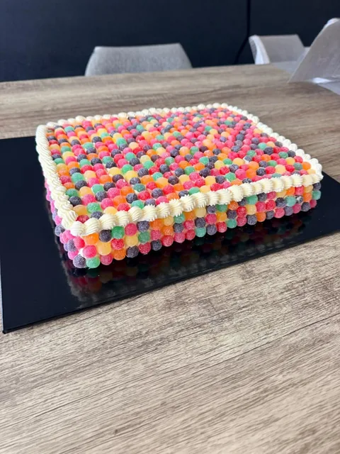 Rectangular slab cake covered in rows of colourful Jelly Tots with a piped white border