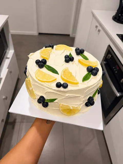 Rustic buttercream cake topped with lemon slices, blueberries and mint