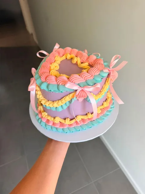 Lilac vintage heart cake piped in coral, aqua and yellow with pink ribbon bows