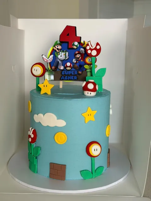 Tall sky-blue Super Mario cake with fondant coins, stars, mushrooms, piranha plants and a Mario and Luigi topper for a fourth birthday